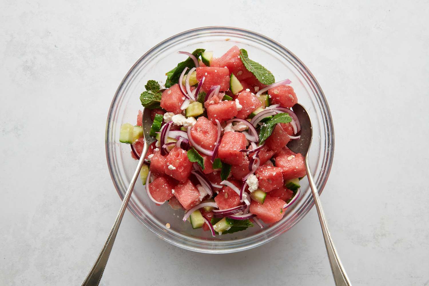 A bowl of watermelon, mint, cucumber, feta, and sliced red onion