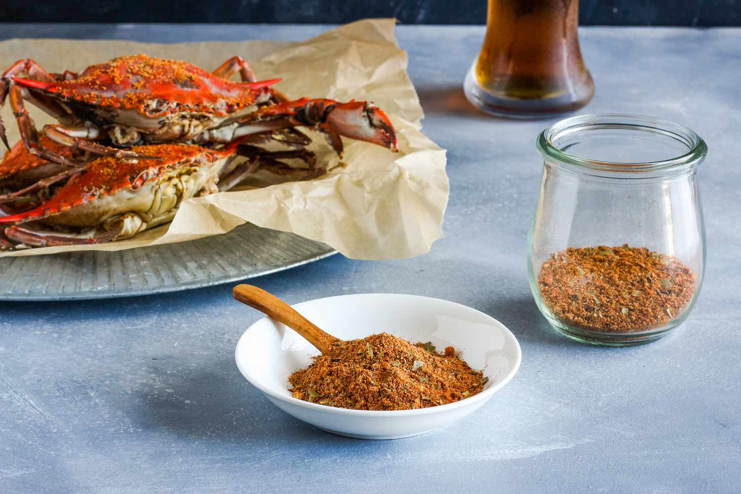 Old Bay-style seasoning mix in a bowl and in a jar, crabs in the background