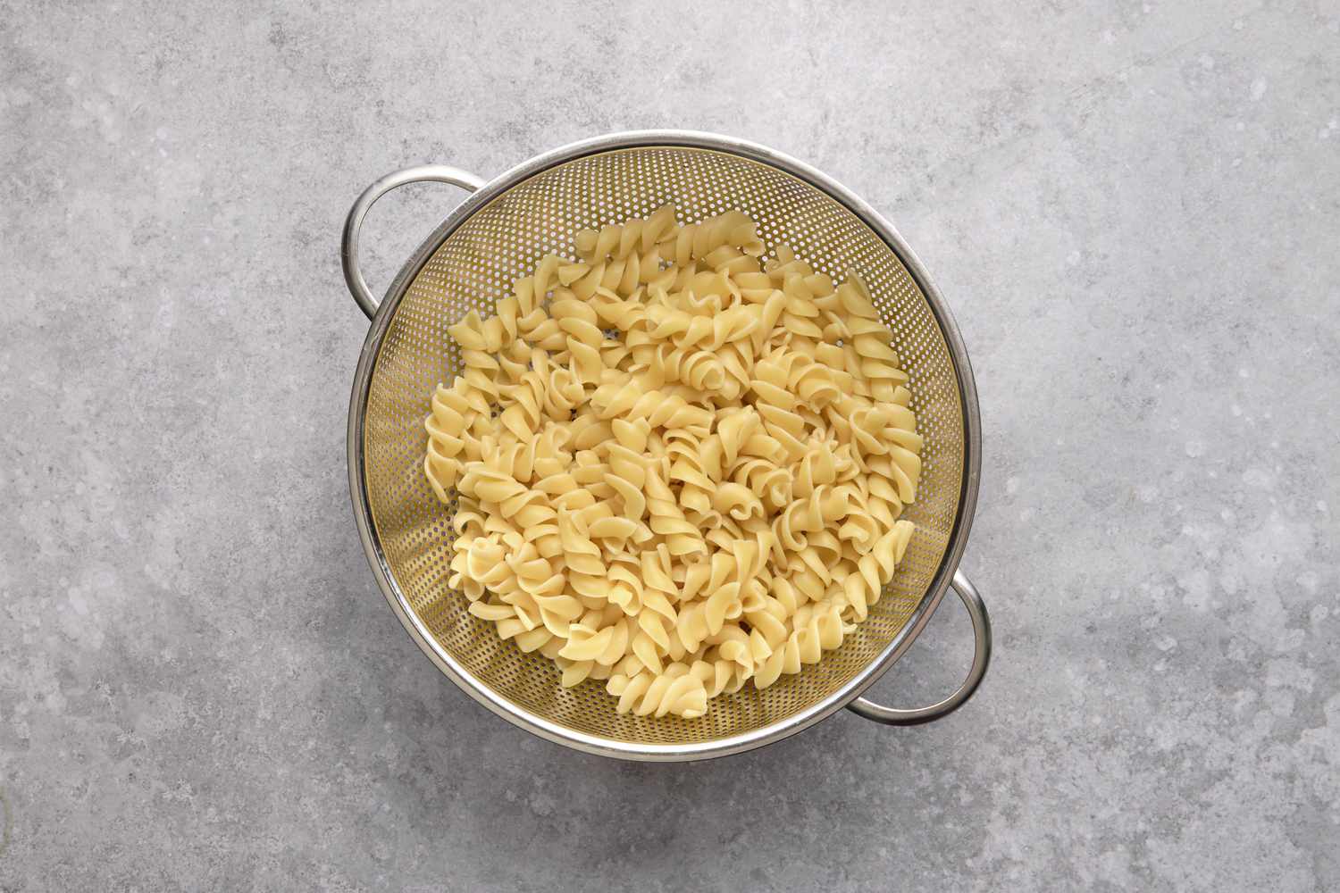 A metal colander with cooked fusilli pasta