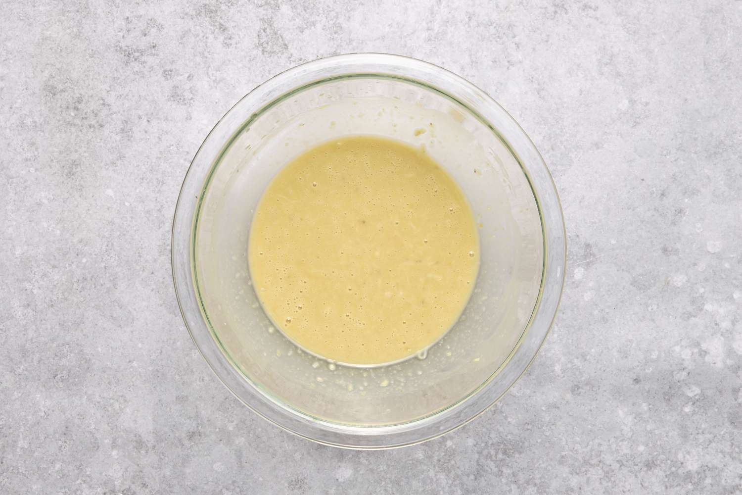 A bowl of dressing made from olive oil, grated Parmigiano-Reggiano, and the lemon-egg yolk mixture